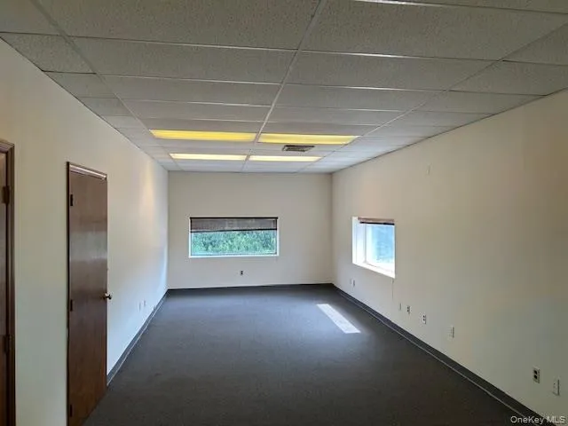Empty room with a paneled ceiling and dark colored carpet Empty room with a paneled ceiling and dark colored carpet