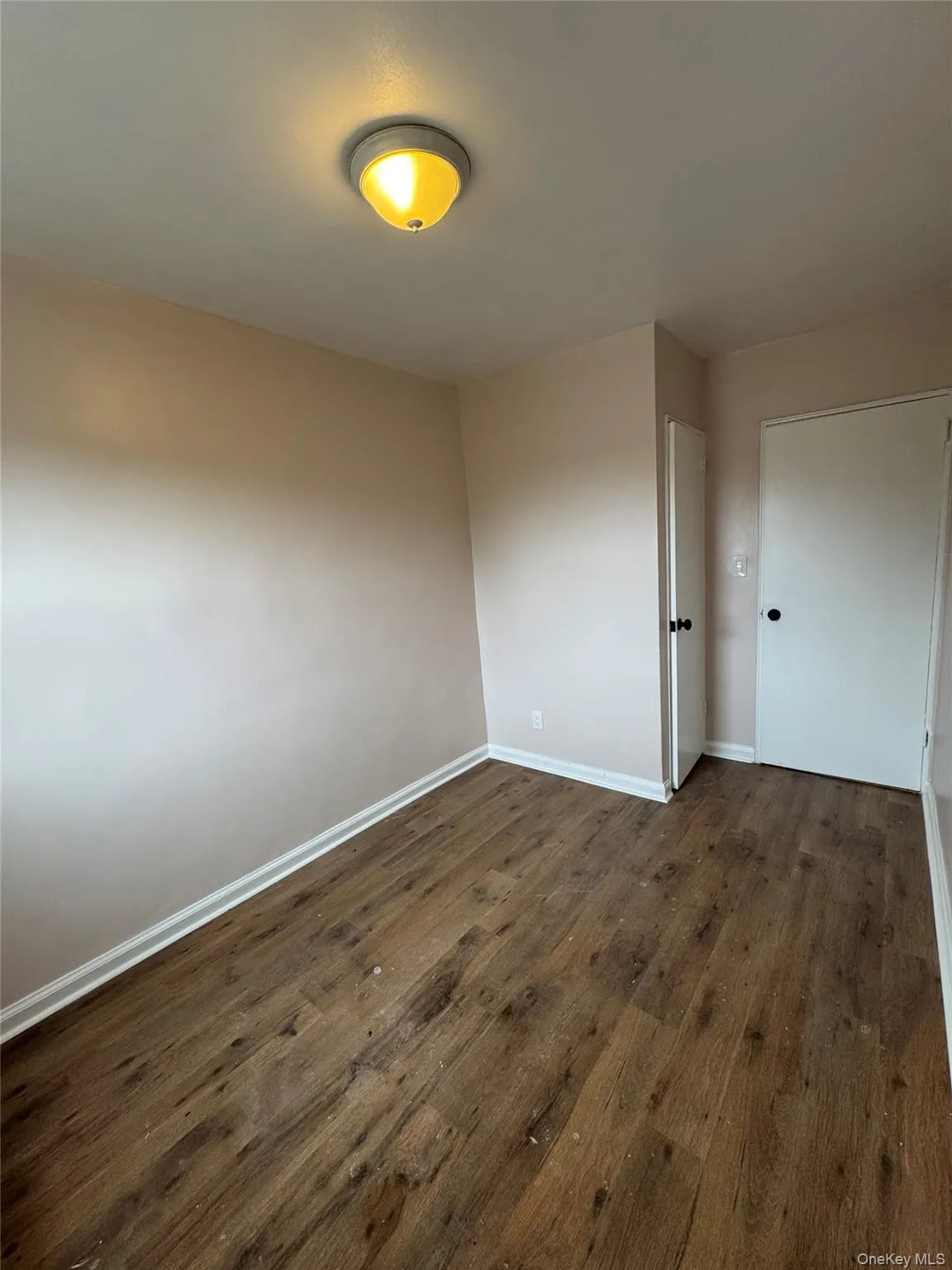 Unfurnished room with dark wood-style flooring and baseboards Unfurnished room with dark wood-style flooring and baseboards