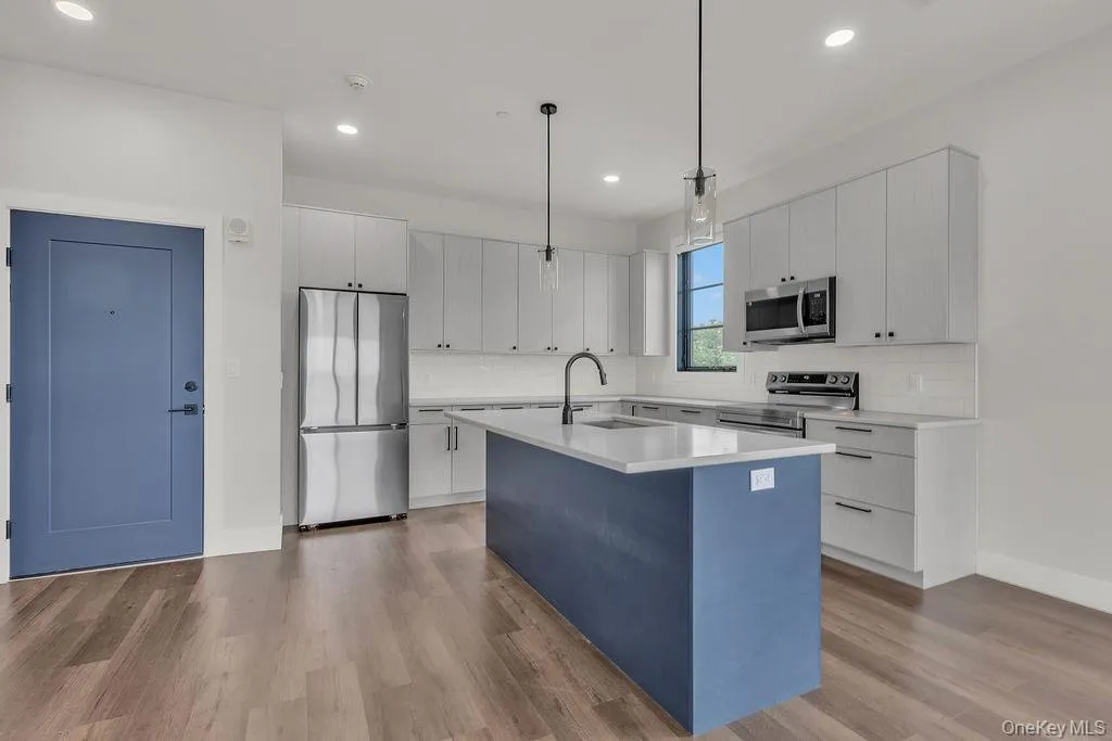 Kitchen featuring appliances with stainless steel finishes, an island with sink, recessed lighting, light countertops, and wood finished floors Kitchen featuring appliances with stainless steel finishes, an island with sink, recessed lighting, light countertops, and wood finished floors