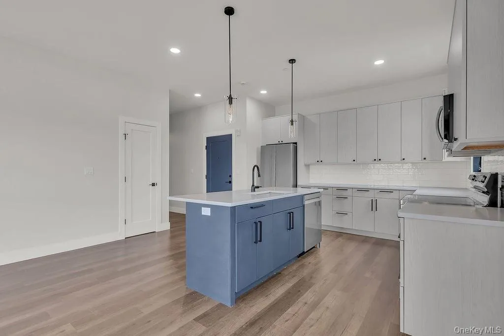 Kitchen featuring a center island with sink, light wood-style floors, tasteful backsplash, stainless steel appliances, and light countertops Kitchen featuring a center island with sink, light wood-style floors, tasteful backsplash, stainless steel appliances, and light countertops