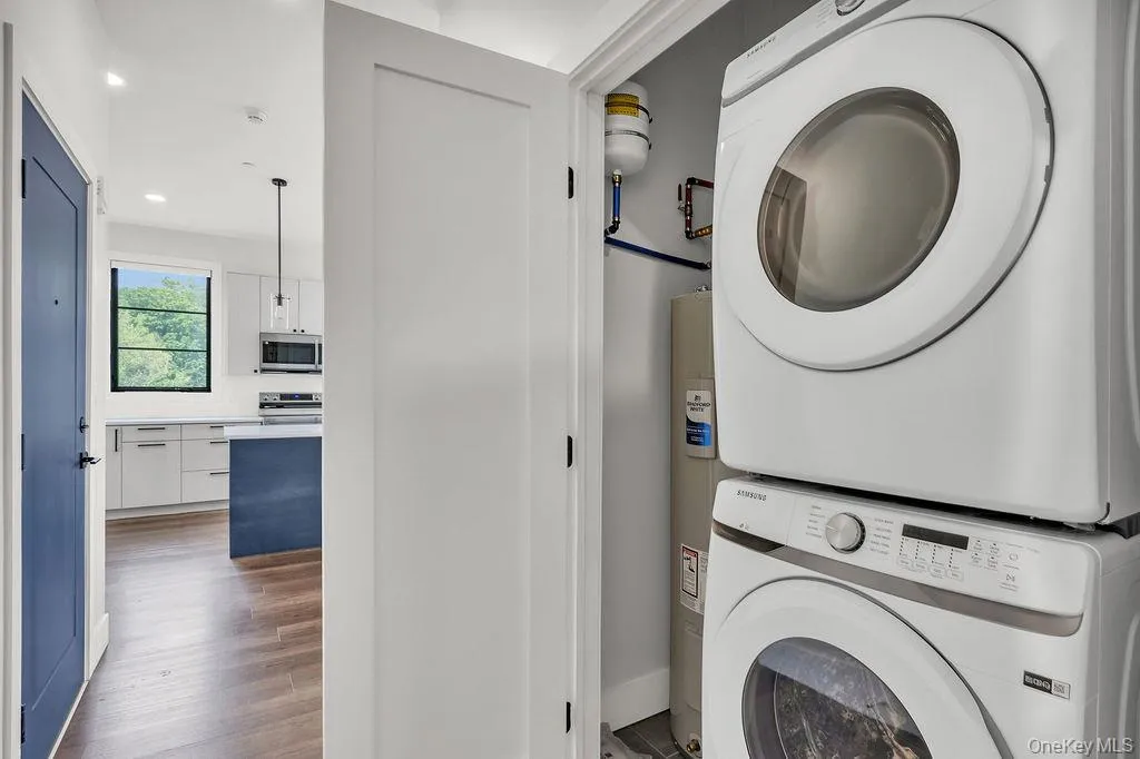 Washroom featuring stacked washer / drying machine, wood finished floors, recessed lighting, and water heater Washroom featuring stacked washer / drying machine, wood finished floors, recessed lighting, and water heater