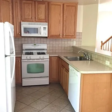 Kitchen featuring white appliances, sink, light tile patterned flooring, and backsplash Kitchen featuring white appliances, sink, light tile patterned flooring, and backsplash