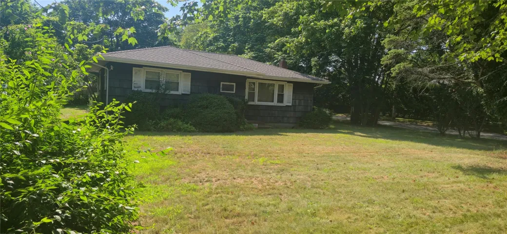 View of front of house featuring a front lawn, a shingled roof, and a chimney