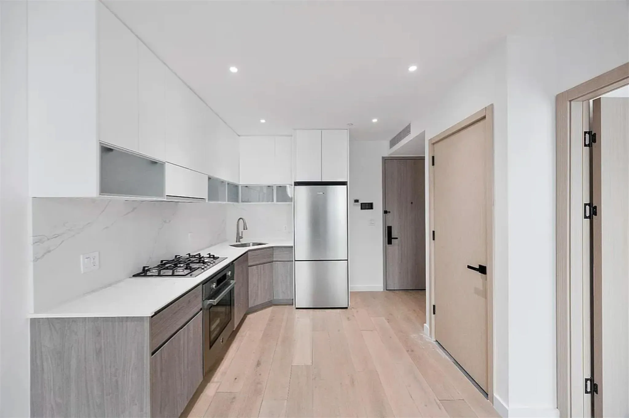 Kitchen with modern cabinets, appliances with stainless steel finishes, light wood-style floors, white cabinets, and recessed lighting Kitchen with modern cabinets, appliances with stainless steel finishes, light wood-style floors, white cabinets, and recessed lighting