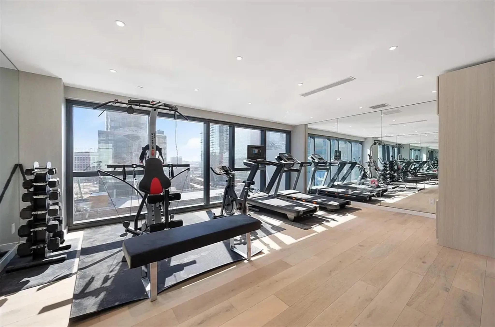Workout area with light wood-style flooring, a view of city, and recessed lighting Workout area with light wood-style flooring, a view of city, and recessed lighting