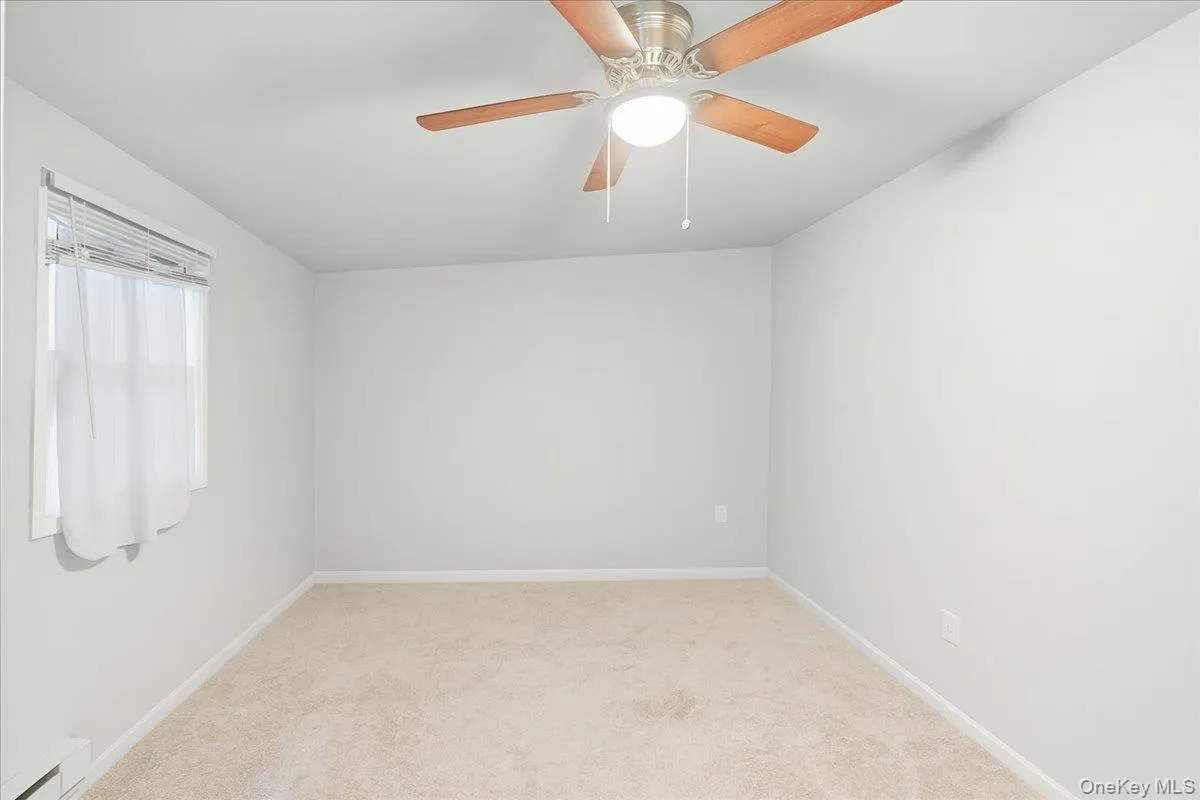 Spare room with light colored carpet, a baseboard heating unit, and a ceiling fan Spare room with light colored carpet, a baseboard heating unit, and a ceiling fan