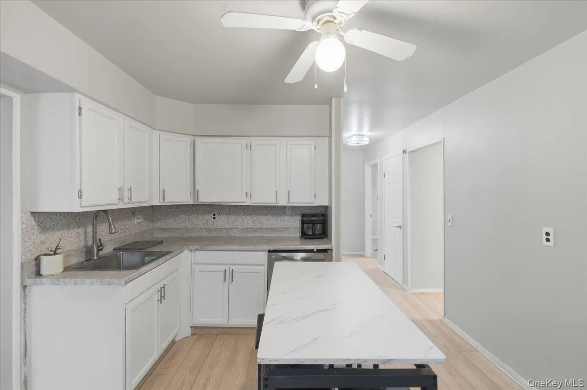 Kitchen with white cabinets, decorative backsplash, and light countertops Kitchen with white cabinets, decorative backsplash, and light countertops