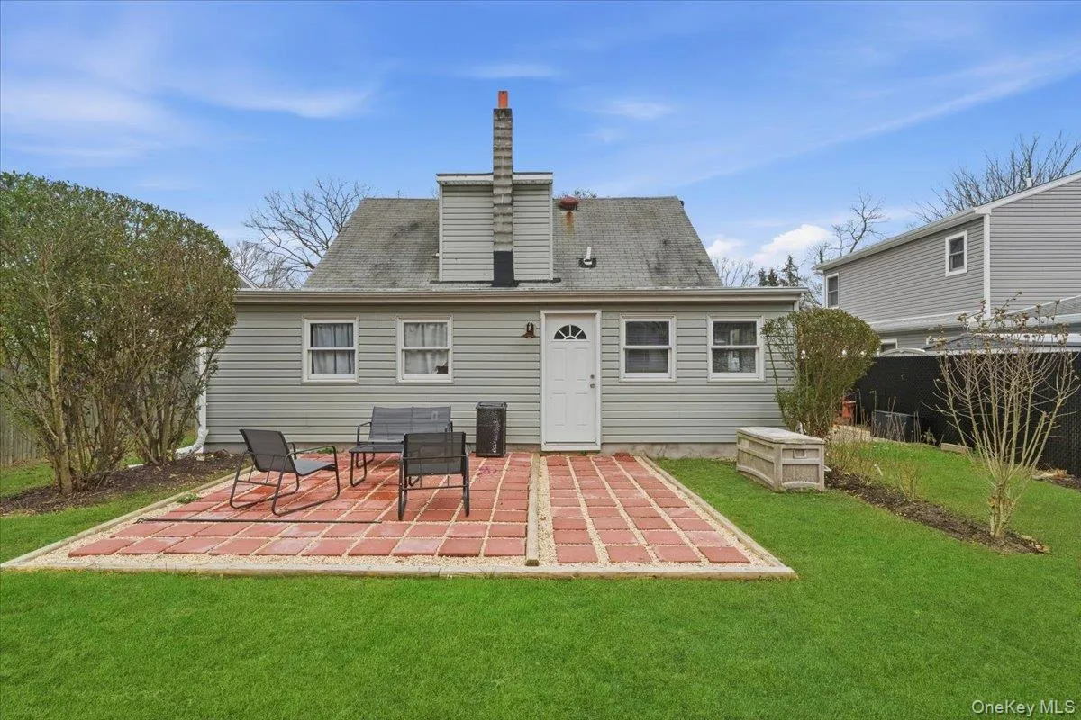 Back of house featuring a patio, roof with shingles, and a chimney Back of house featuring a patio, roof with shingles, and a chimney