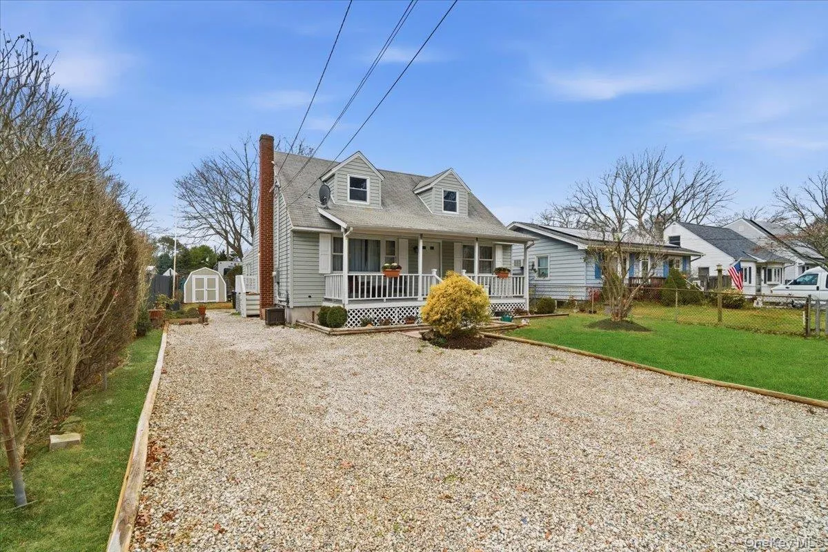 Cape cod house with a porch, a storage shed, a chimney, and gravel driveway Cape cod house with a porch, a storage shed, a chimney, and gravel driveway