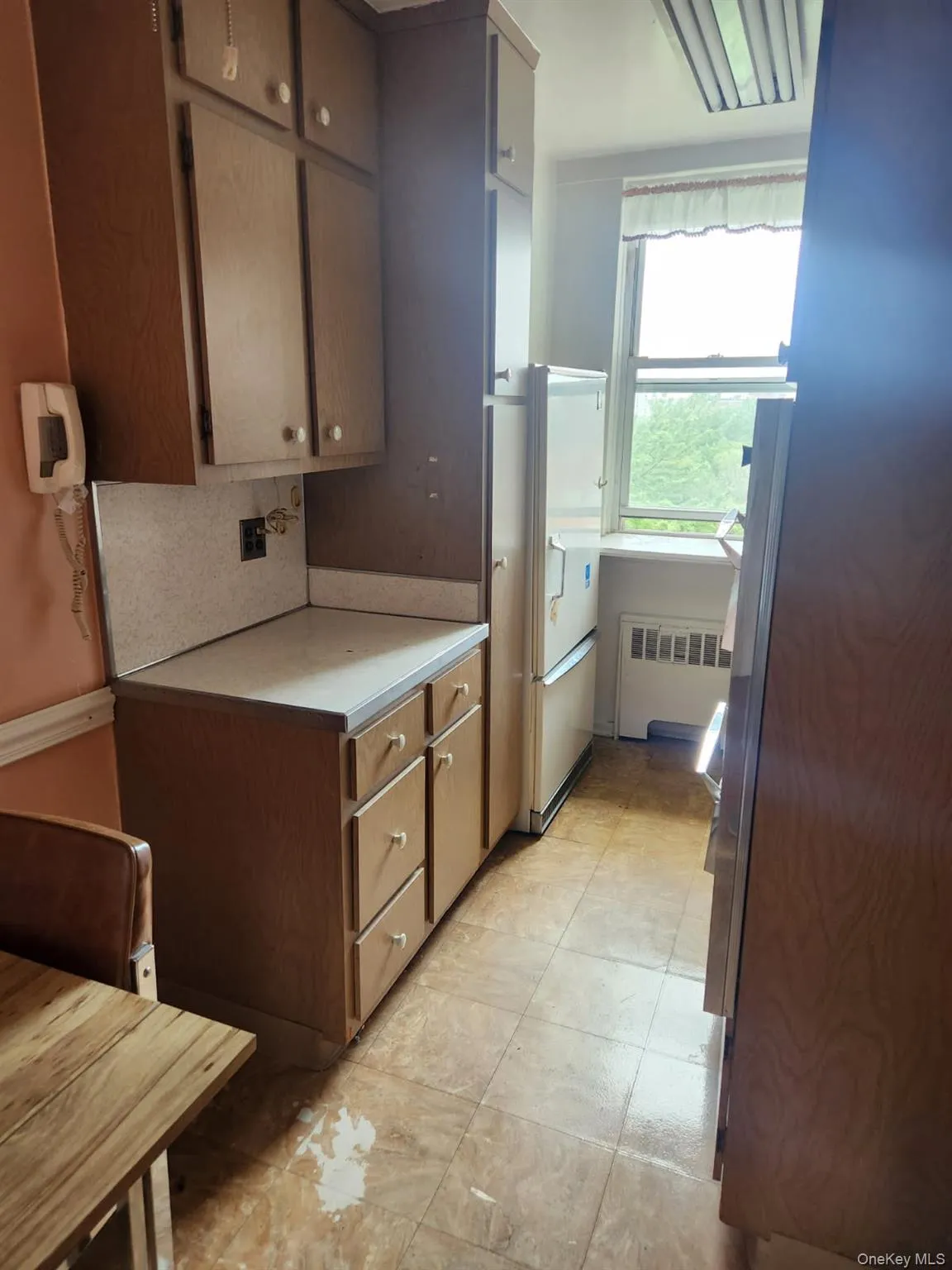 Kitchen with radiator heating unit, light countertops, decorative backsplash, and freestanding refrigerator Kitchen with radiator heating unit, light countertops, decorative backsplash, and freestanding refrigerator
