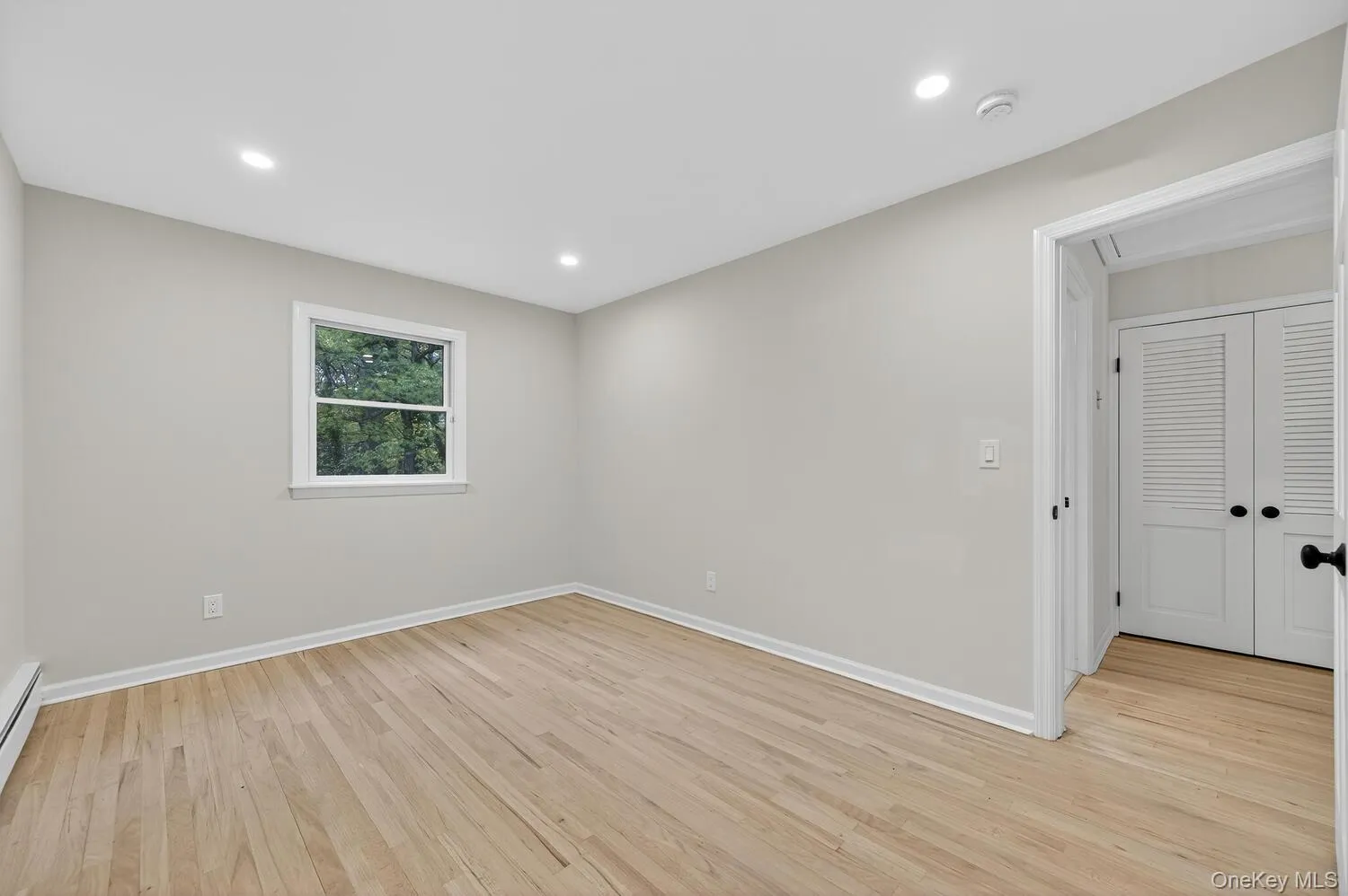 Unfurnished room with light wood finished floors, recessed lighting, and baseboard heating Unfurnished room with light wood finished floors, recessed lighting, and baseboard heating