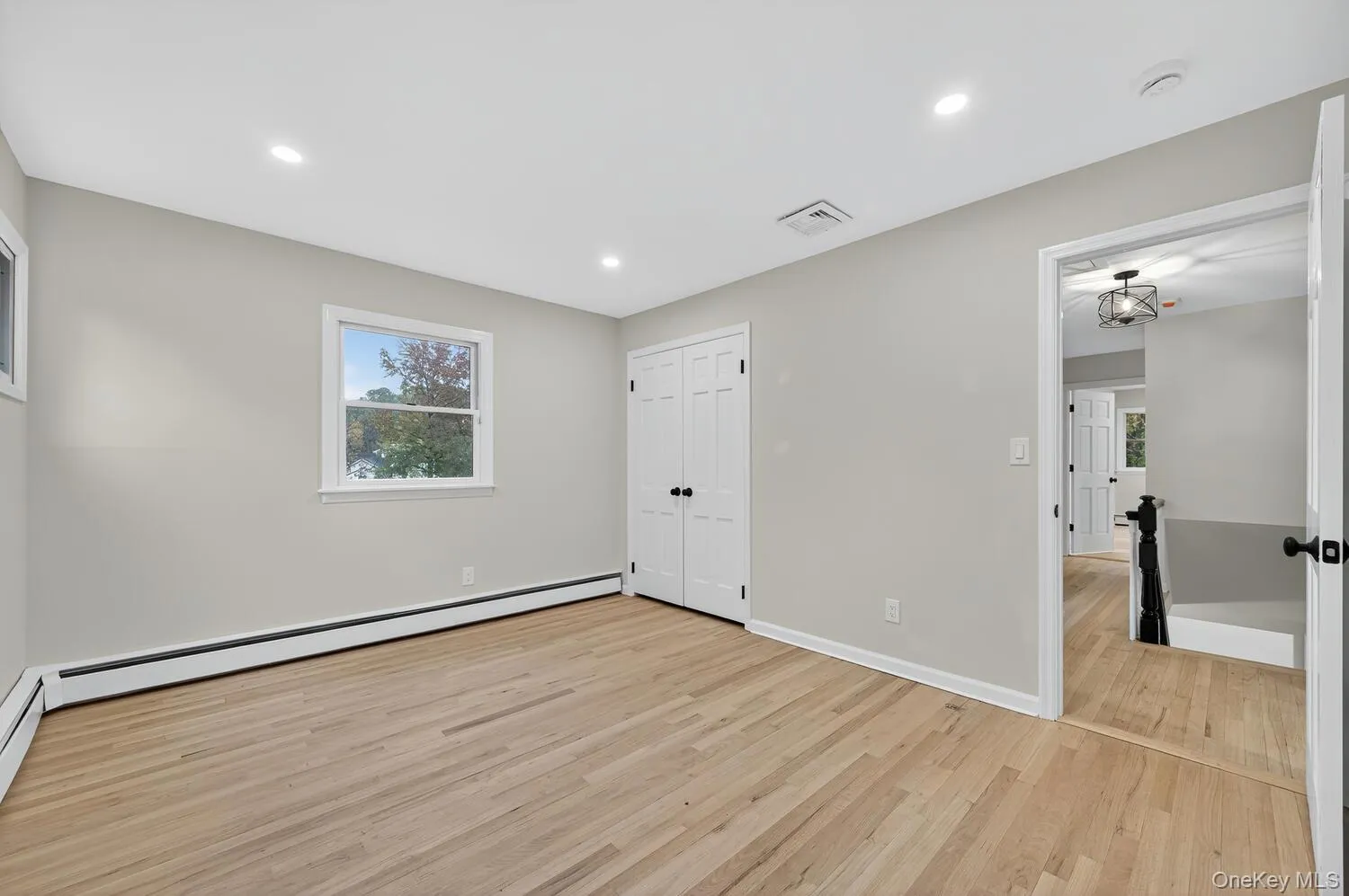 Unfurnished bedroom with light wood-style flooring, recessed lighting, a baseboard heating unit, and a closet Unfurnished bedroom with light wood-style flooring, recessed lighting, a baseboard heating unit, and a closet