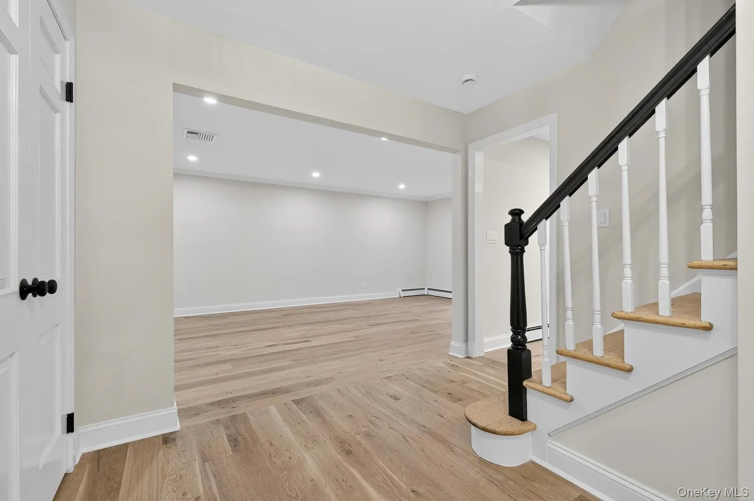 Foyer featuring light wood-type flooring, stairs, recessed lighting, and baseboard heating Foyer featuring light wood-type flooring, stairs, recessed lighting, and baseboard heating
