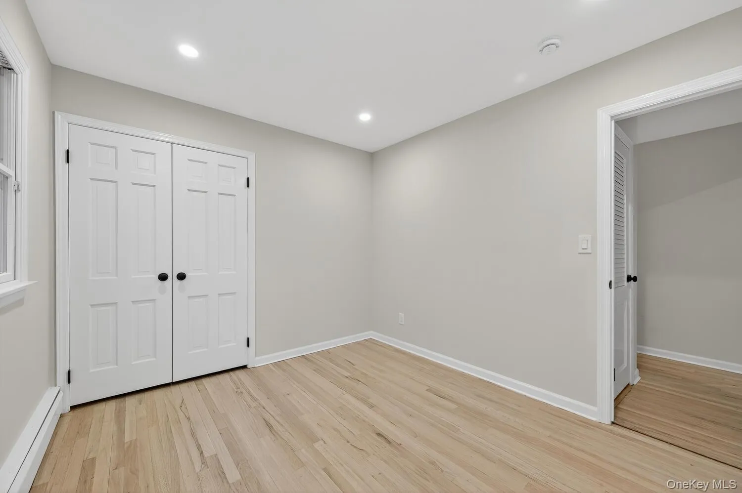 Unfurnished bedroom with baseboard heating, light wood-style flooring, a closet, and recessed lighting Unfurnished bedroom with baseboard heating, light wood-style flooring, a closet, and recessed lighting