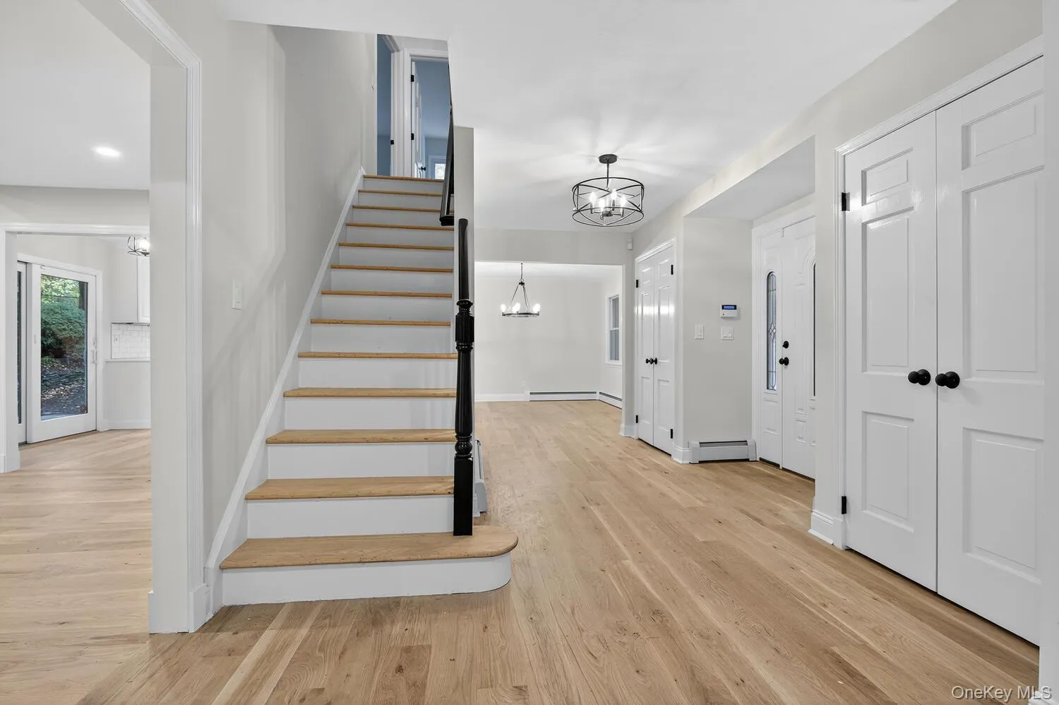 Stairway featuring a chandelier, wood finished floors, and a baseboard radiator Stairway featuring a chandelier, wood finished floors, and a baseboard radiator