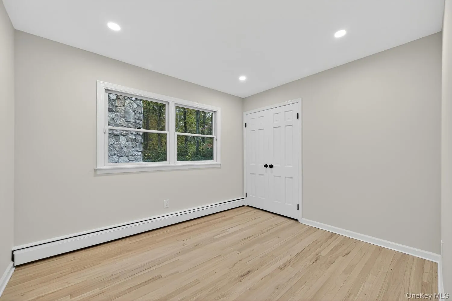 Unfurnished bedroom with a baseboard radiator, light wood-style flooring, recessed lighting, and a closet Unfurnished bedroom with a baseboard radiator, light wood-style flooring, recessed lighting, and a closet