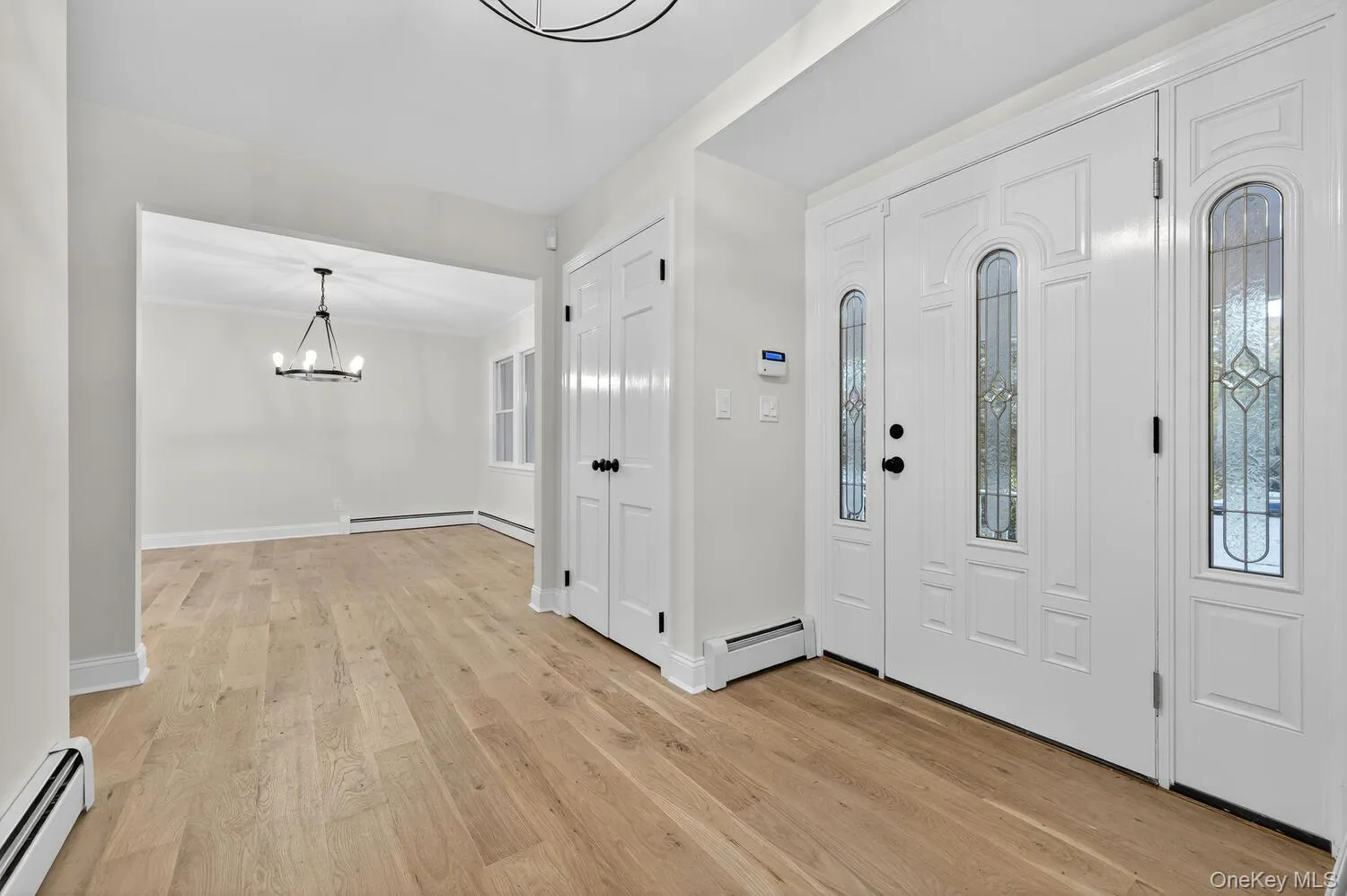 Entryway with baseboard heating, light wood-style flooring, and a chandelier Entryway with baseboard heating, light wood-style flooring, and a chandelier