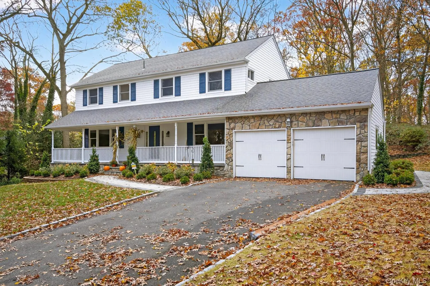 View of front of property featuring a porch, stone siding, an attached garage, asphalt driveway, and a shingled roof View of front of property featuring a porch, stone siding, an attached garage, asphalt driveway, and a shingled roof