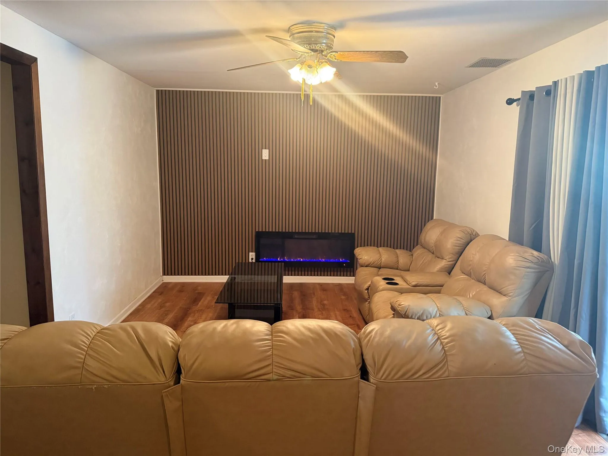 Cinema featuring a ceiling fan, wood finished floors, and a glass covered fireplace Cinema featuring a ceiling fan, wood finished floors, and a glass covered fireplace