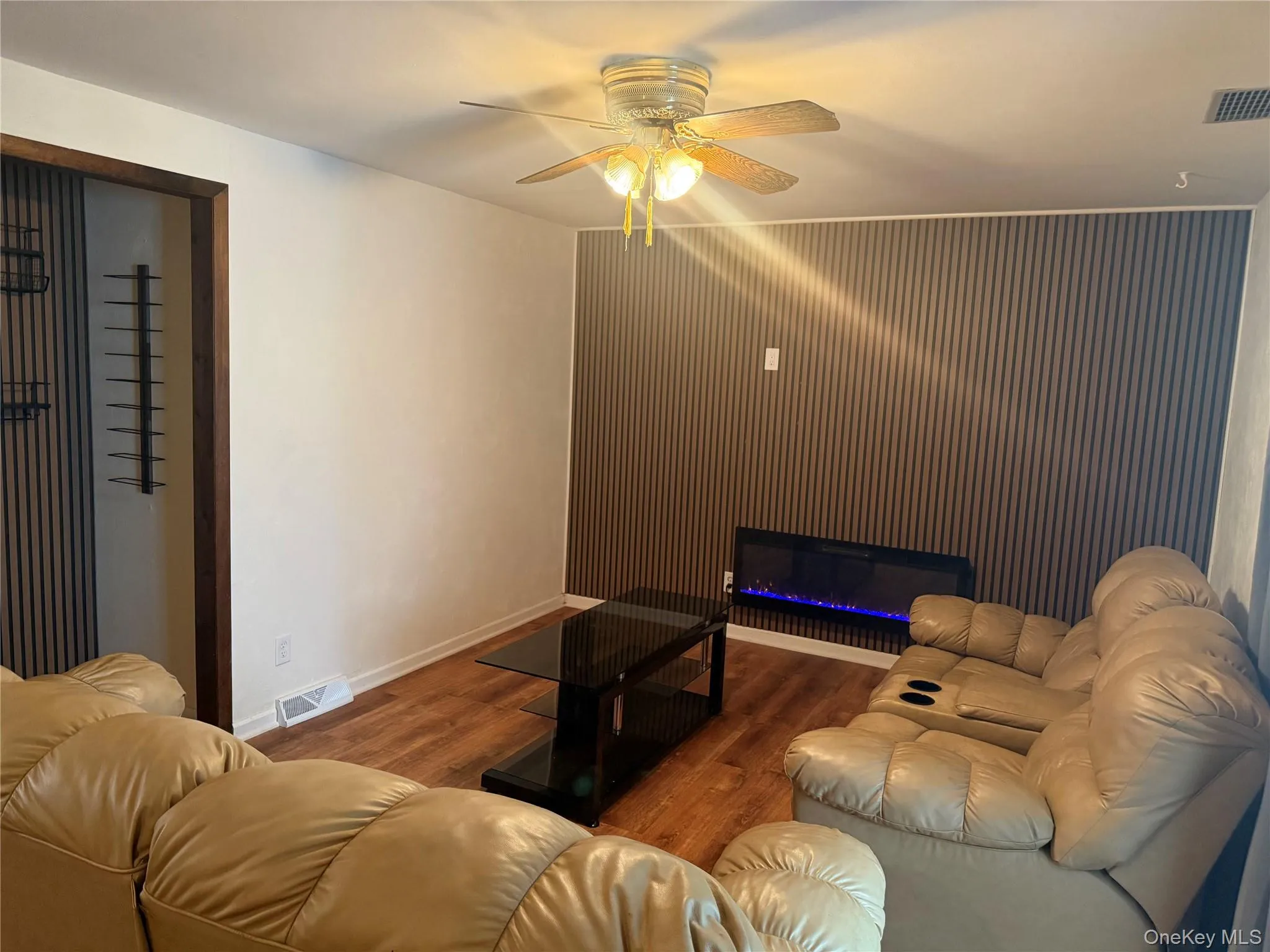 Living room with ceiling fan, wood finished floors, and a glass covered fireplace Living room with ceiling fan, wood finished floors, and a glass covered fireplace