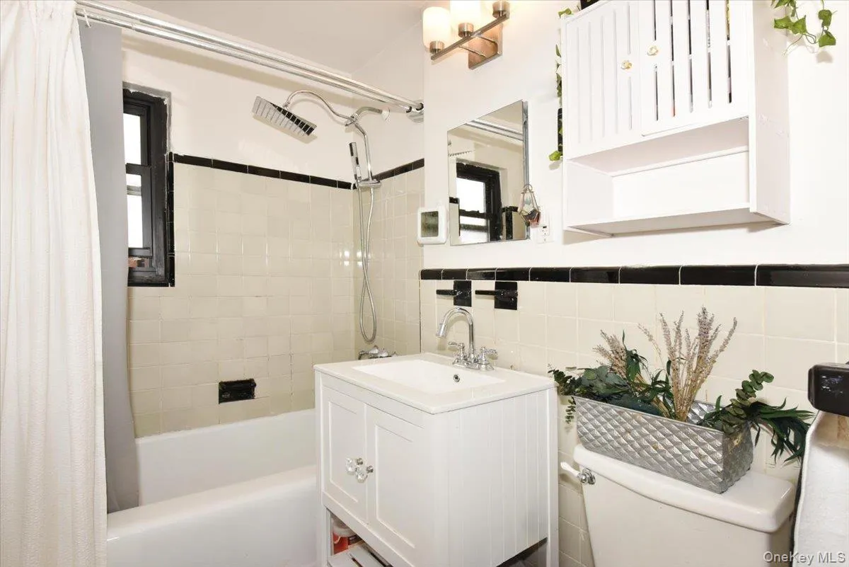Bathroom featuring vanity, shower / bath combo, and tile walls Bathroom featuring vanity, shower / bath combo, and tile walls
