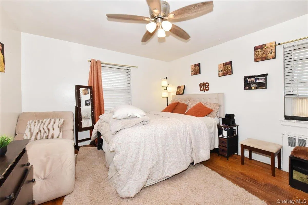 Bedroom with wood finished floors, a ceiling fan, and radiator Bedroom with wood finished floors, a ceiling fan, and radiator