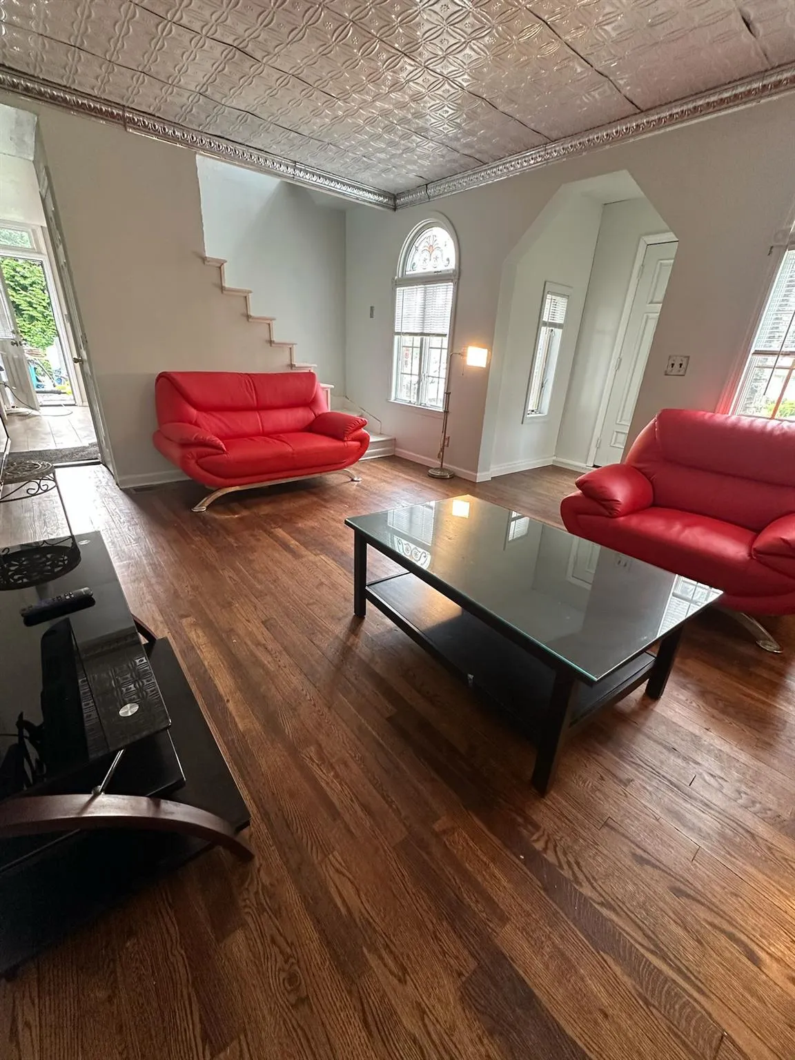 Living room with an ornate ceiling, wood finished floors, arched walkways, crown molding, and stairs Living room with an ornate ceiling, wood finished floors, arched walkways, crown molding, and stairs