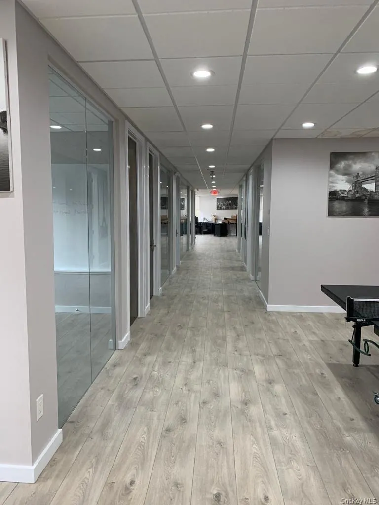 Corridor featuring a paneled ceiling, recessed lighting, and light wood-style floors Corridor featuring a paneled ceiling, recessed lighting, and light wood-style floors