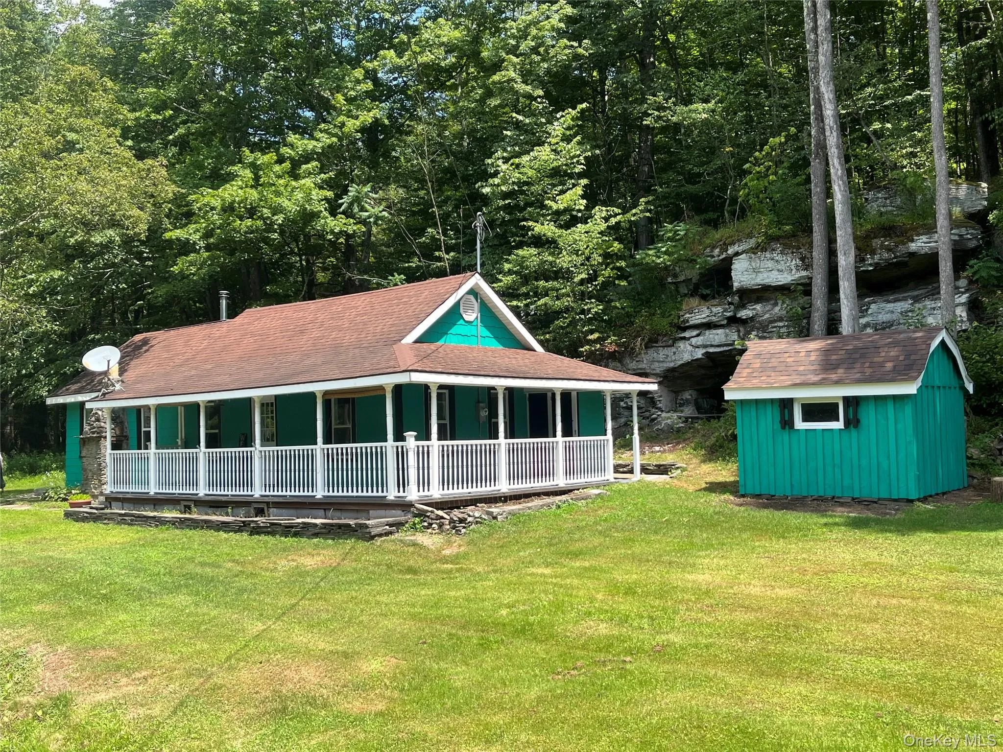 Back of property with a yard, a storage unit, roof with shingles, and covered porch Back of property with a yard, a storage unit, roof with shingles, and covered porch
