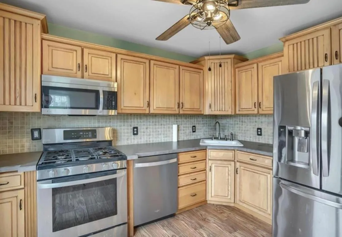 Kitchen with stainless steel appliances, light wood-style flooring, light brown cabinets, and a ceiling fan Kitchen with stainless steel appliances, light wood-style flooring, light brown cabinets, and a ceiling fan