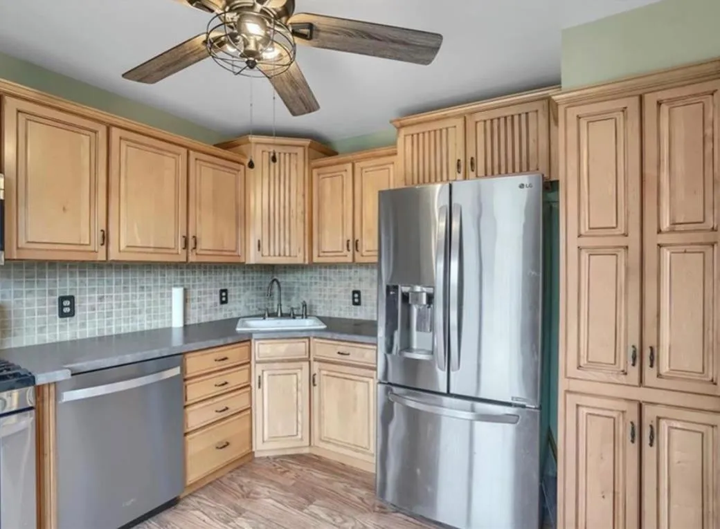 Kitchen with appliances with stainless steel finishes, light brown cabinetry, light wood-style floors, and tasteful backsplash Kitchen with appliances with stainless steel finishes, light brown cabinetry, light wood-style floors, and tasteful backsplash
