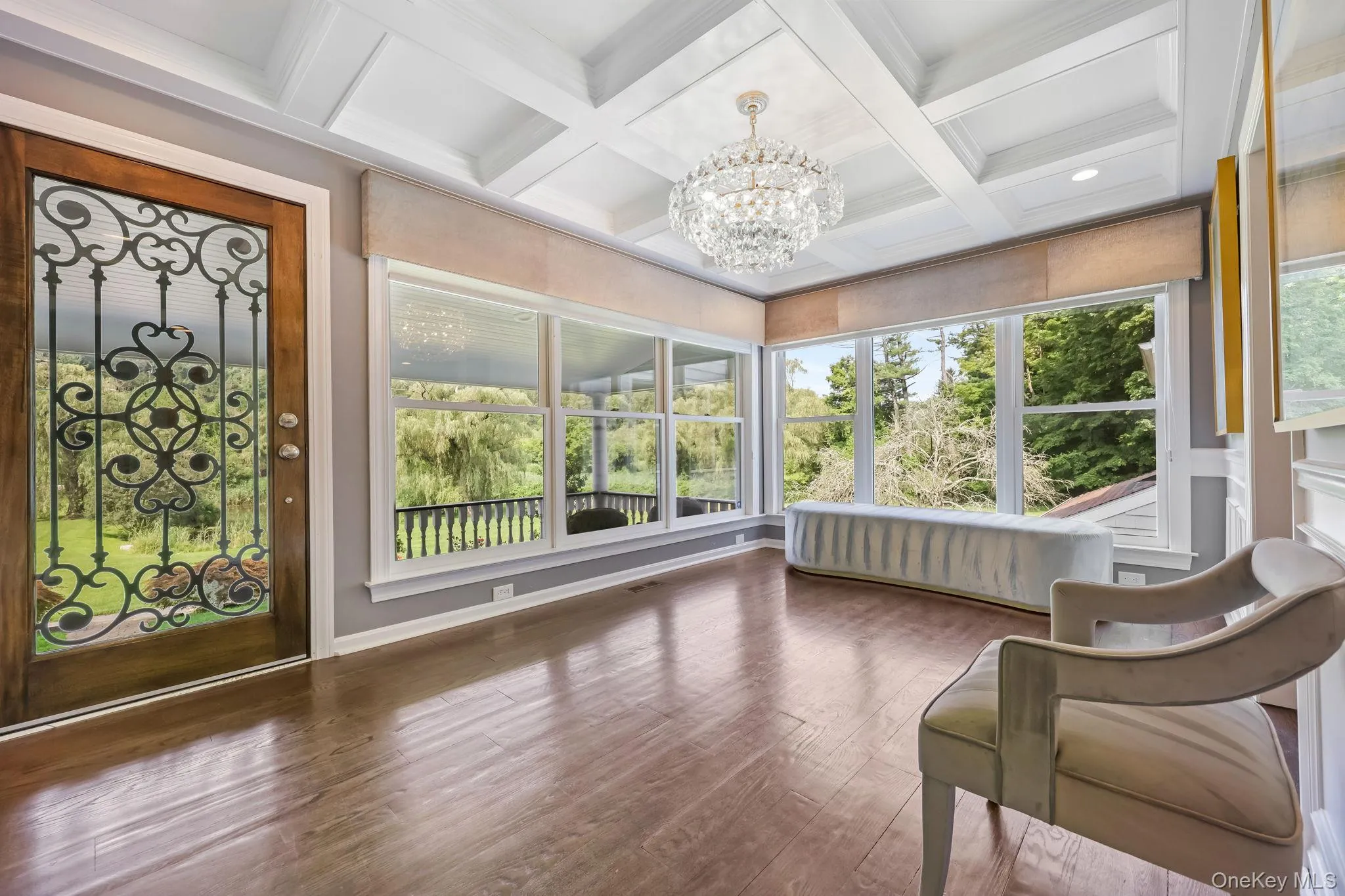 Sunroom / solarium with a chandelier, wood finished floors, beamed ceiling, and coffered ceiling Sunroom / solarium with a chandelier, wood finished floors, beamed ceiling, and coffered ceiling