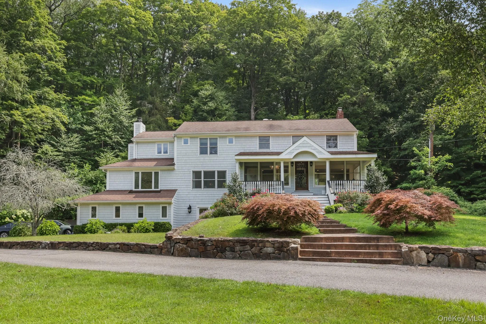 View of front of home featuring a chimney, covered porch, a front lawn, stairway, and roof with shingles View of front of home featuring a chimney, covered porch, a front lawn, stairway, and roof with shingles