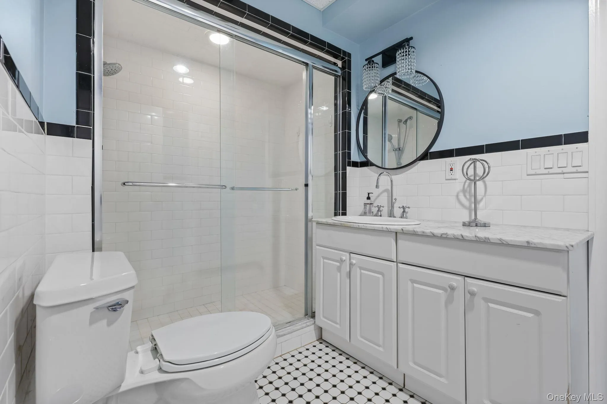Full bath with tile walls, vanity, a stall shower, and light tile patterned floors Full bath with tile walls, vanity, a stall shower, and light tile patterned floors