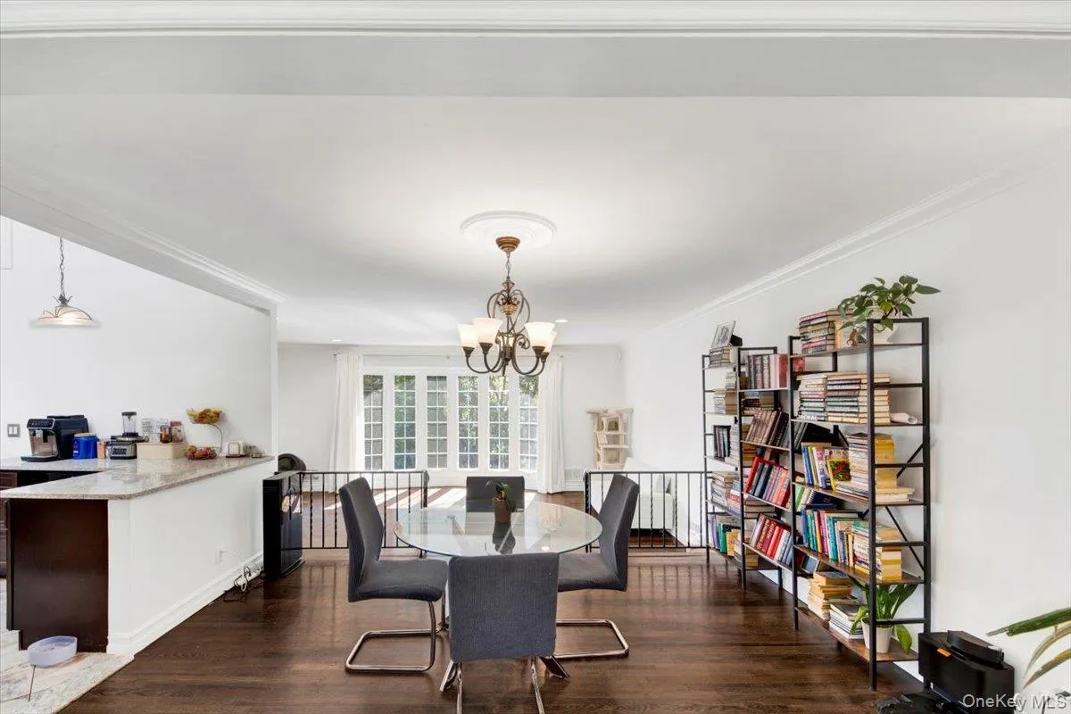 Dining space with dark wood-type flooring, ornamental molding, and a chandelier Dining space with dark wood-type flooring, ornamental molding, and a chandelier