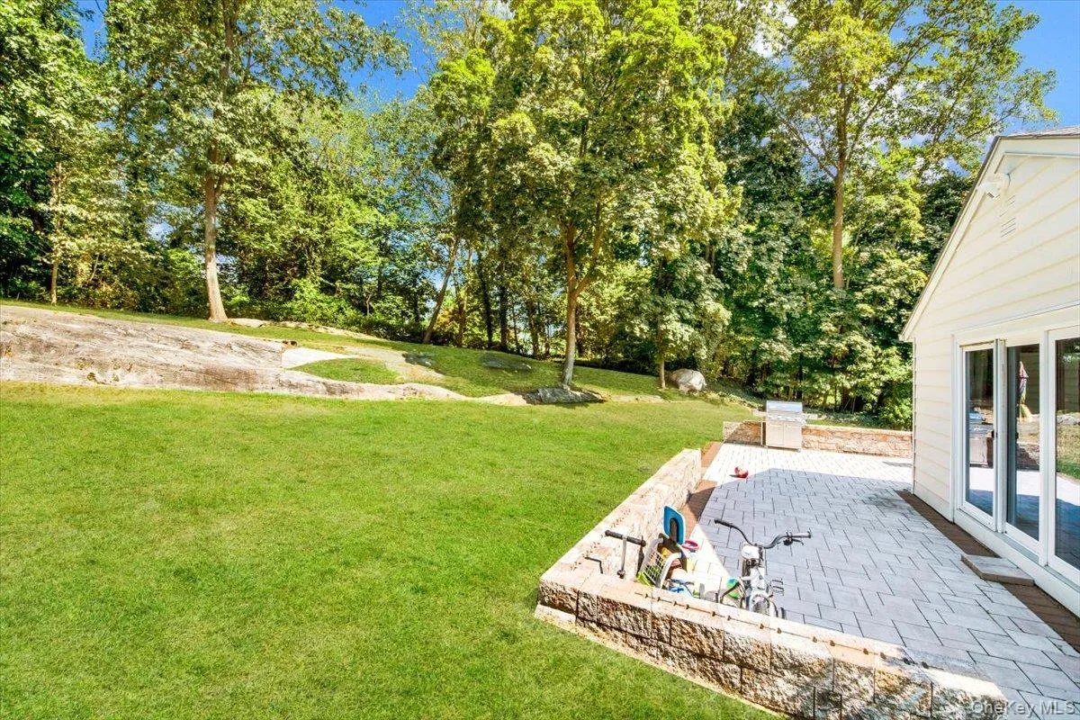 View of green lawn featuring a patio area View of green lawn featuring a patio area