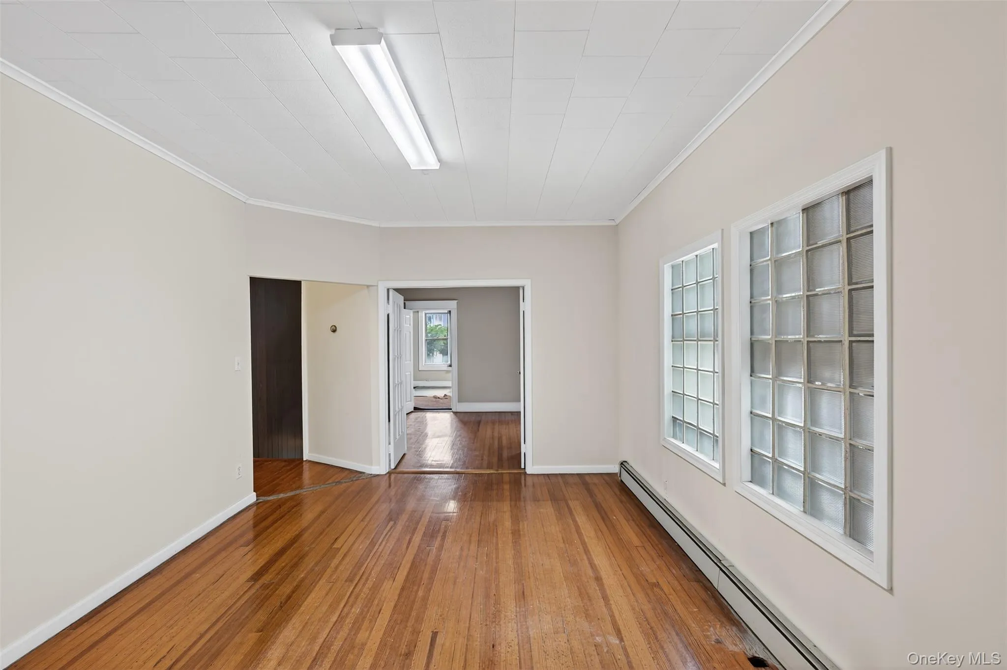 Spare room featuring a baseboard radiator, hardwood / wood-style floors, and crown molding Spare room featuring a baseboard radiator, hardwood / wood-style floors, and crown molding