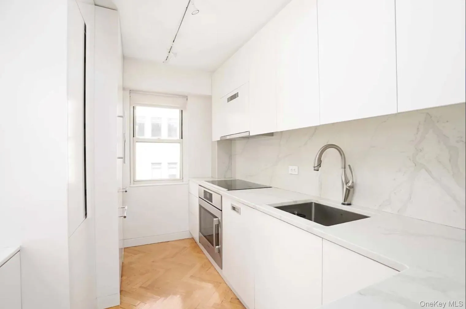 Kitchen featuring modern cabinets, white cabinetry, stainless steel oven, and tasteful backsplash Kitchen featuring modern cabinets, white cabinetry, stainless steel oven, and tasteful backsplash