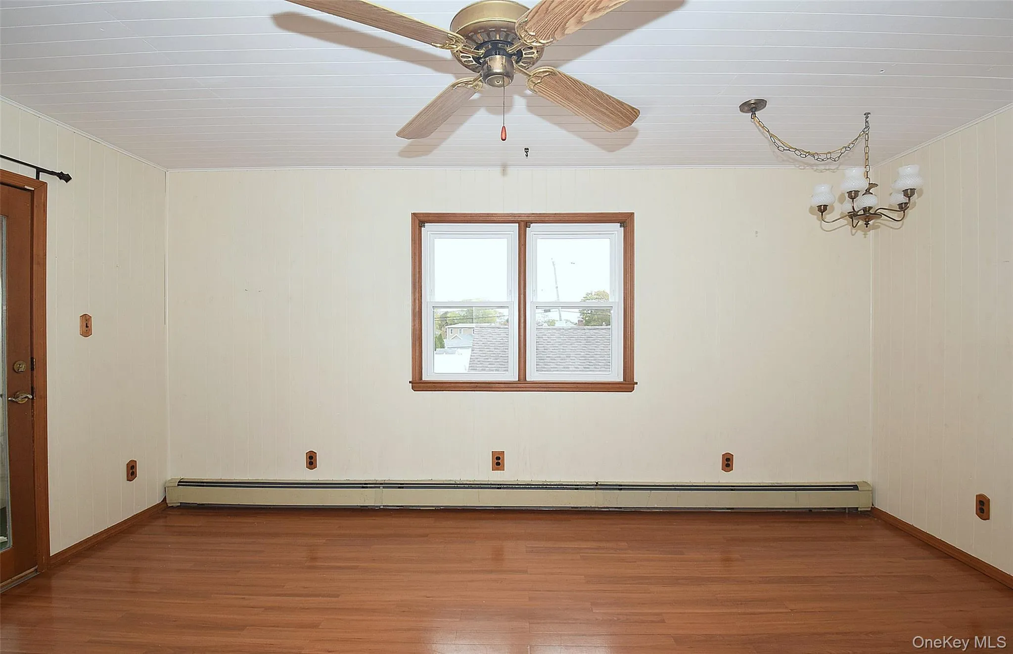 Unfurnished room with wood finished floors, a chandelier, a baseboard heating unit, and ceiling fan Unfurnished room with wood finished floors, a chandelier, a baseboard heating unit, and ceiling fan