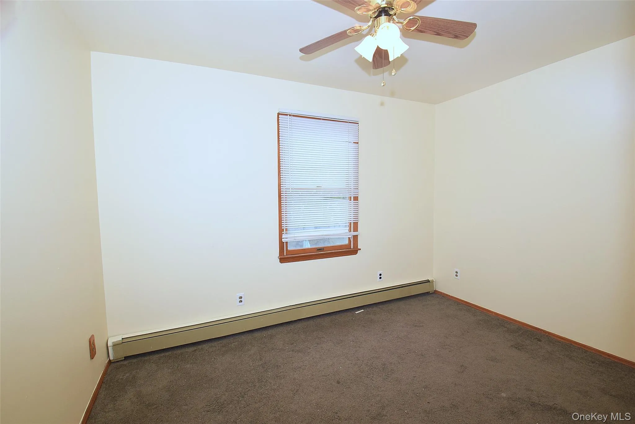 Carpeted empty room featuring baseboard heating and a ceiling fan Carpeted empty room featuring baseboard heating and a ceiling fan