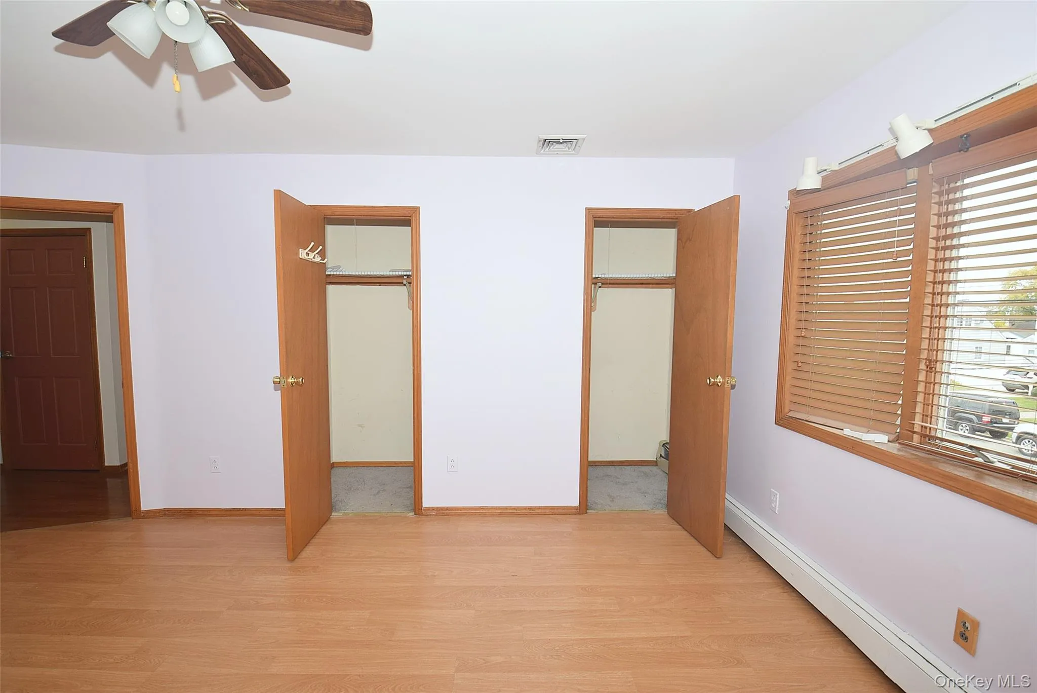 Unfurnished bedroom featuring baseboard heating, light wood finished floors, ceiling fan, and a spacious closet Unfurnished bedroom featuring baseboard heating, light wood finished floors, ceiling fan, and a spacious closet