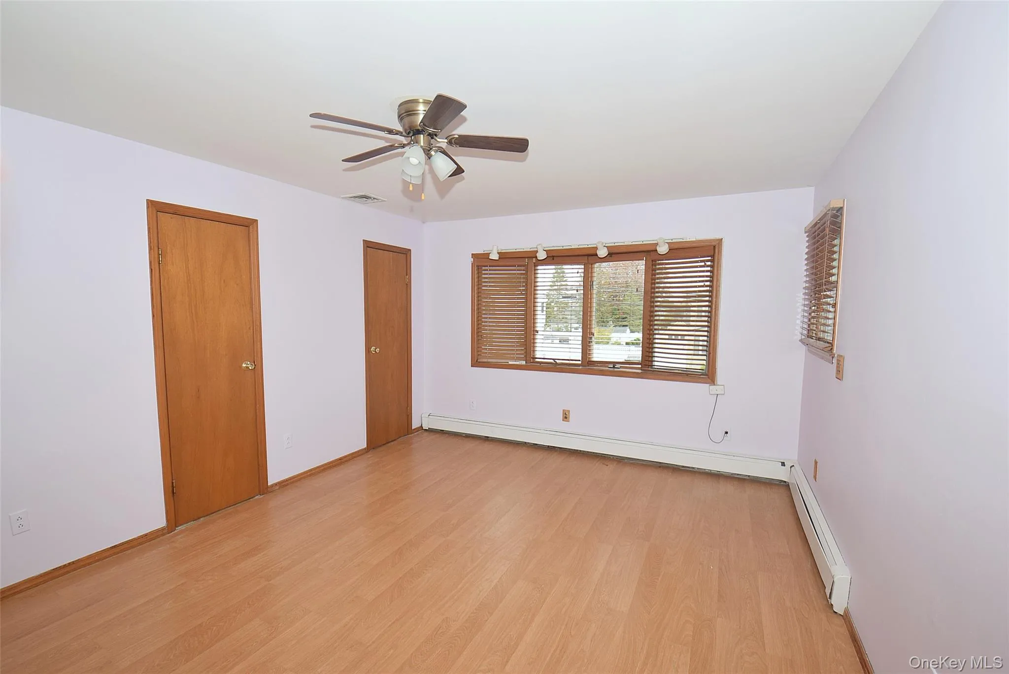 Unfurnished room featuring light wood finished floors, a baseboard heating unit, and ceiling fan Unfurnished room featuring light wood finished floors, a baseboard heating unit, and ceiling fan