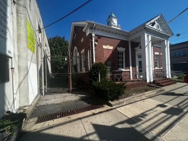 View of property exterior with a chimney, a porch, brick siding, and a gate View of property exterior with a chimney, a porch, brick siding, and a gate