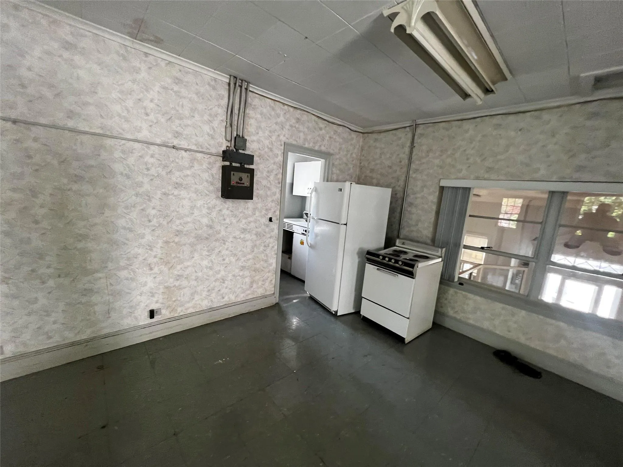 Kitchen featuring white appliances, wallpapered walls, dark floors, and crown molding Kitchen featuring white appliances, wallpapered walls, dark floors, and crown molding