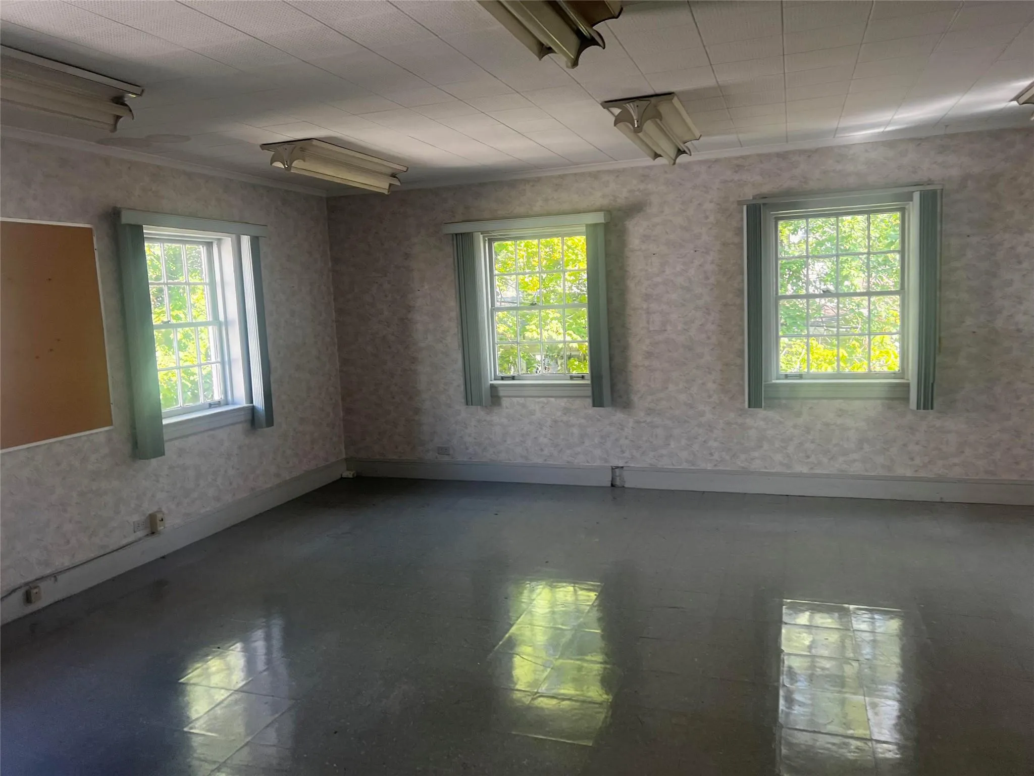 Unfurnished room featuring plenty of natural light and wallpapered walls Unfurnished room featuring plenty of natural light and wallpapered walls