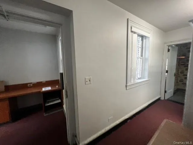 Hallway featuring dark carpet and baseboards Hallway featuring dark carpet and baseboards