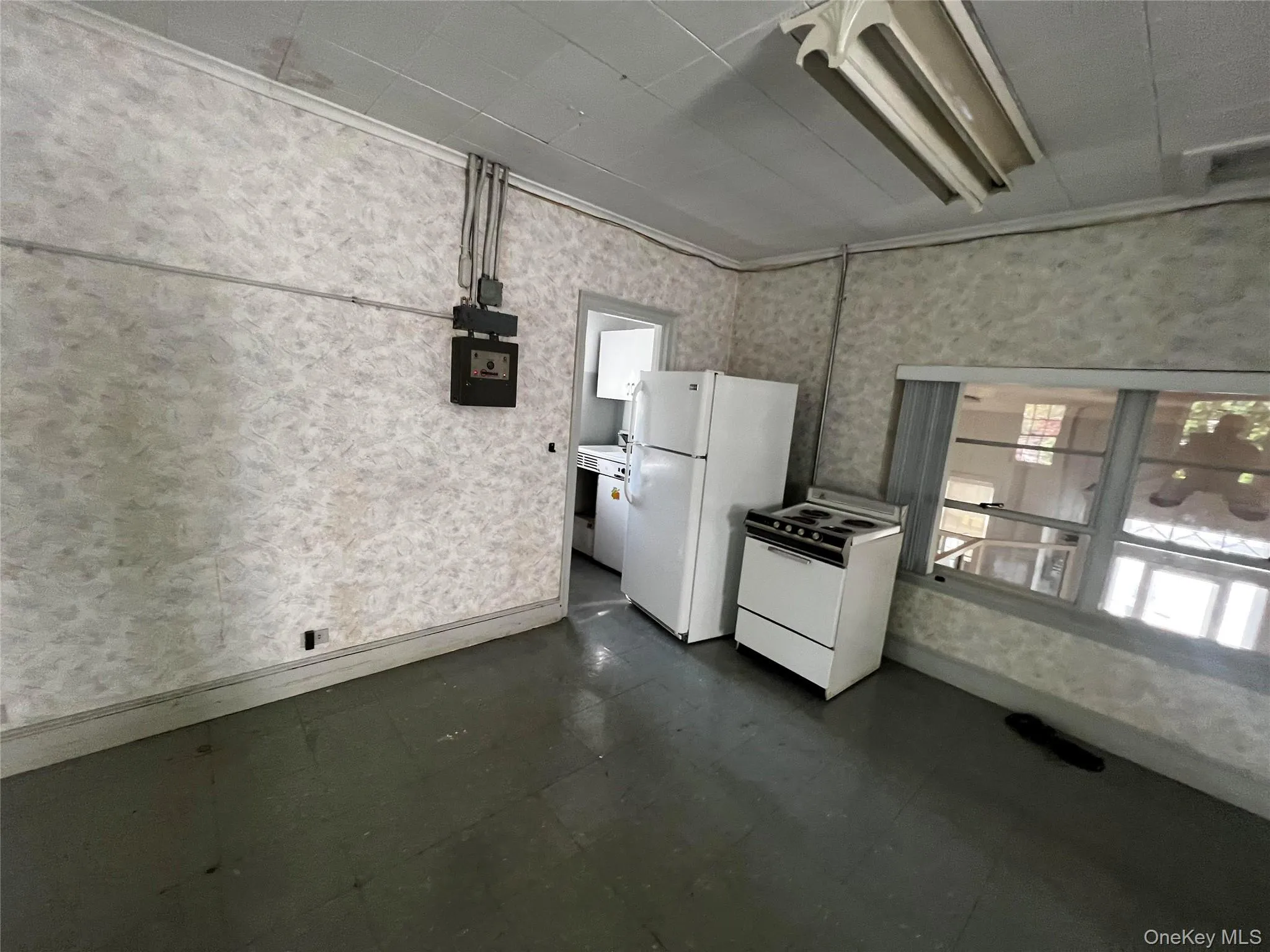 Kitchen featuring white appliances, wallpapered walls, dark floors, and crown molding Kitchen featuring white appliances, wallpapered walls, dark floors, and crown molding