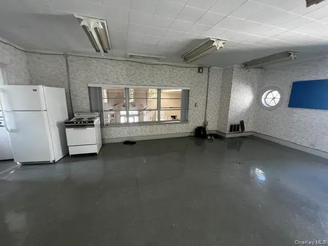 Unfurnished living room with healthy amount of natural light, wallpapered walls, and concrete floors Unfurnished living room with healthy amount of natural light, wallpapered walls, and concrete floors