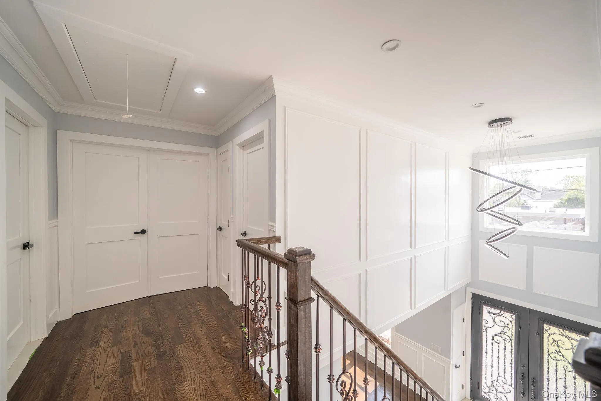 Corridor with attic access, a decorative wall, dark wood-style flooring, recessed lighting, and ornamental molding Corridor with attic access, a decorative wall, dark wood-style flooring, recessed lighting, and ornamental molding