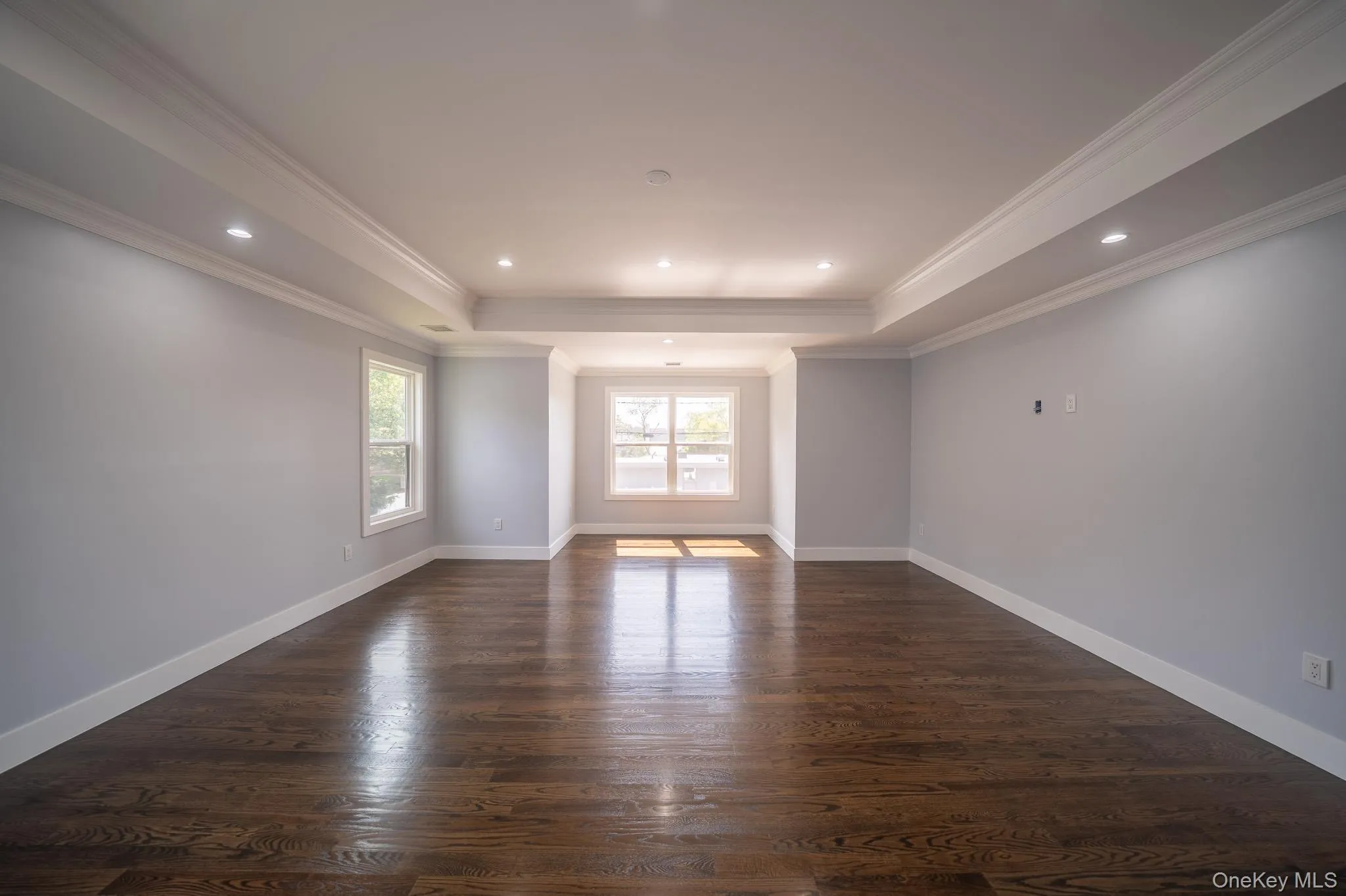 Unfurnished room featuring recessed lighting, dark wood-type flooring, ornamental molding, and a tray ceiling Unfurnished room featuring recessed lighting, dark wood-type flooring, ornamental molding, and a tray ceiling